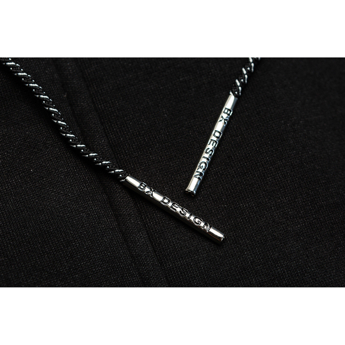 Close-up of black-and-white twisted drawcords with silver metal tips on black fabric.