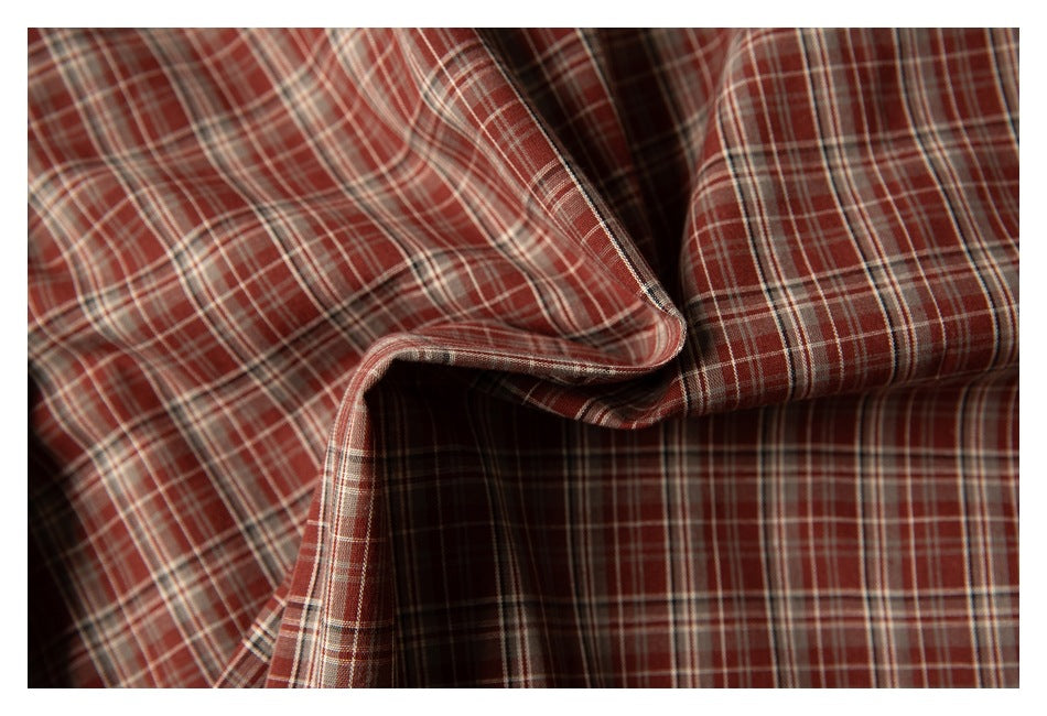 Close-up of folded reddish-brown plaid fabric with cream and dark intersecting stripes.