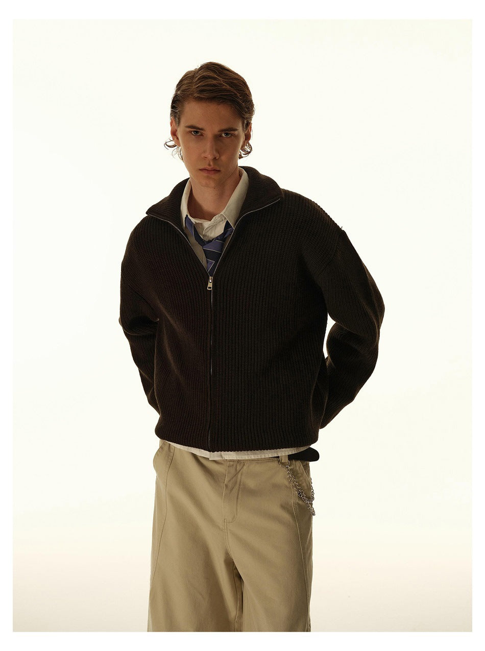 Closer view of a model wearing a dark ribbed zip-front sweater over a shirt and striped tie.