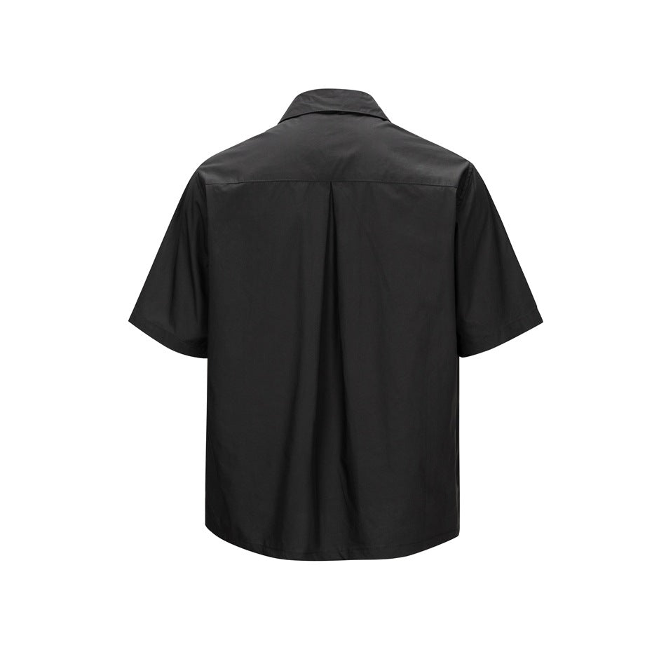 Back view of a plain black short-sleeve button-up shirt with a center pleat.
