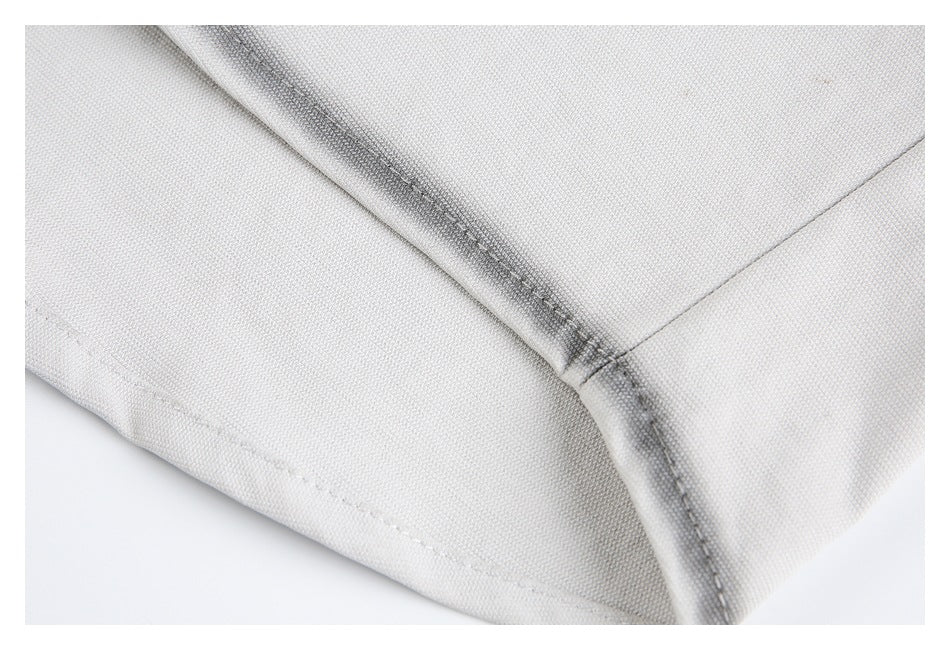 Close-up of a light gray garment seam with visible stitching and folded fabric edges.