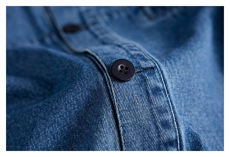 Close-up of a black button and stitched placket on blue denim.