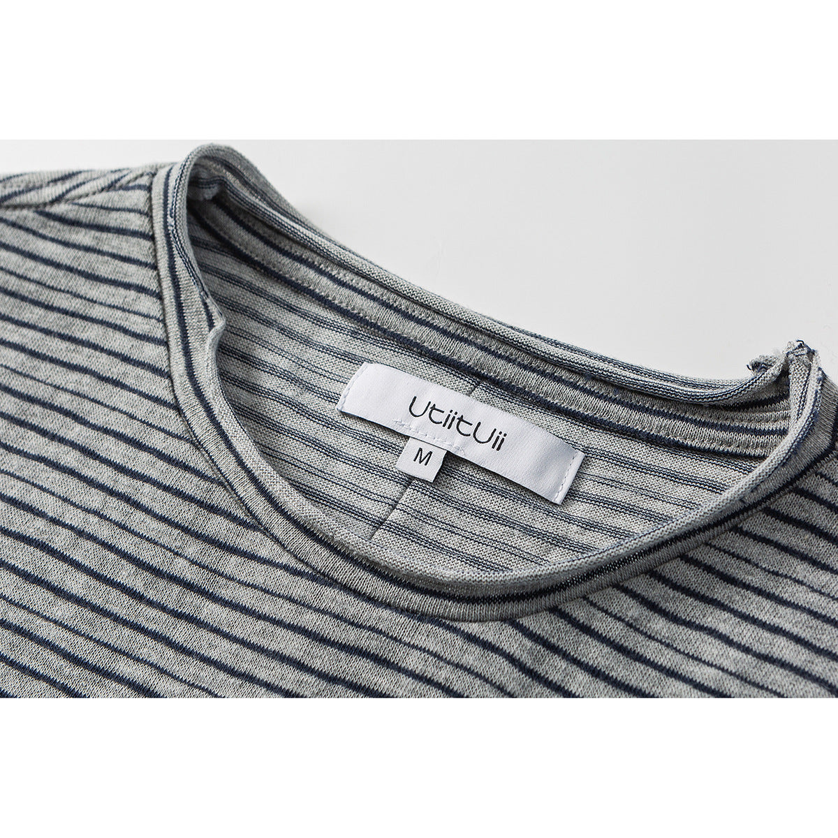 Close-up of a gray-and-white striped shirt neckline with a visible brand and size label.