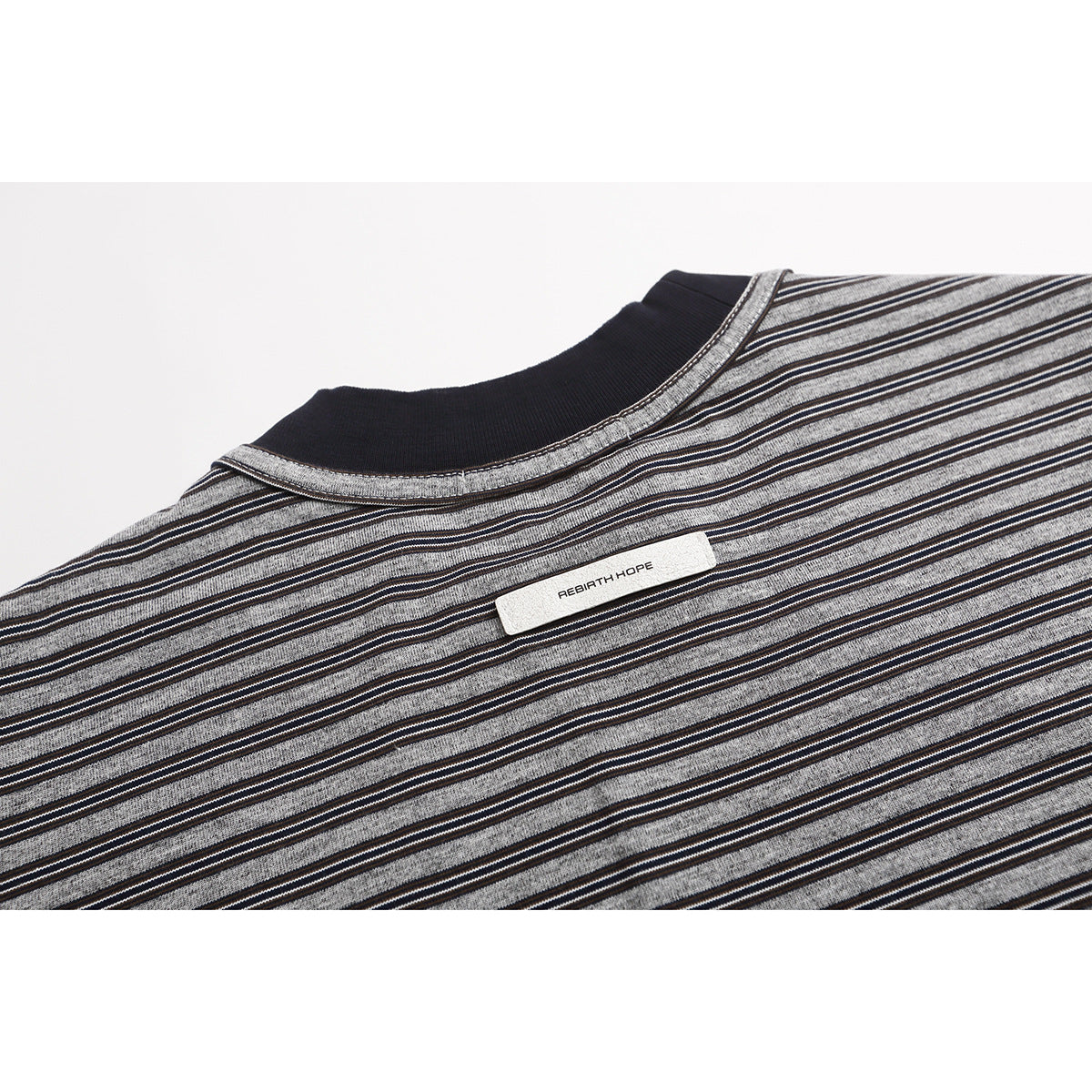 Close-up of the striped T-shirt's upper back, black collar, and small sewn label.