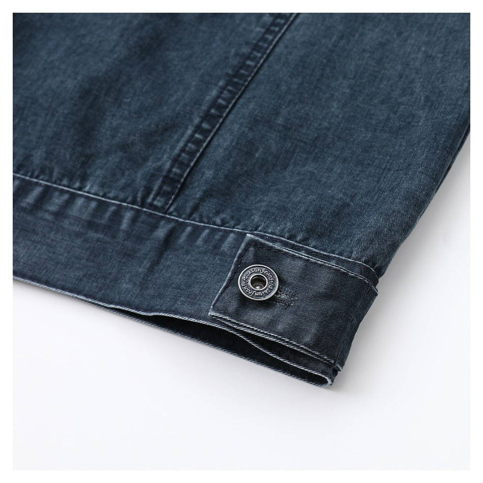 Close-up of dark indigo denim stitching and hem tab with a round engraved metal button.