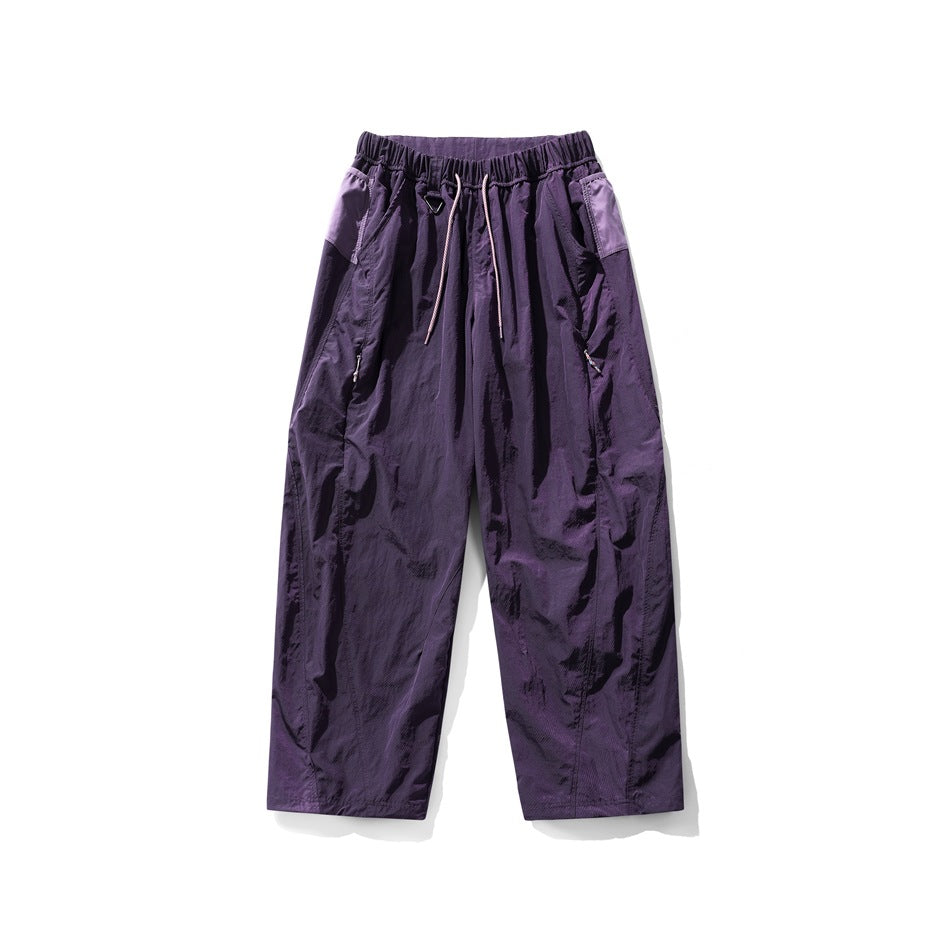 Deep purple wide-leg drawstring pants with lilac side panels and zip pockets, flat lay front view