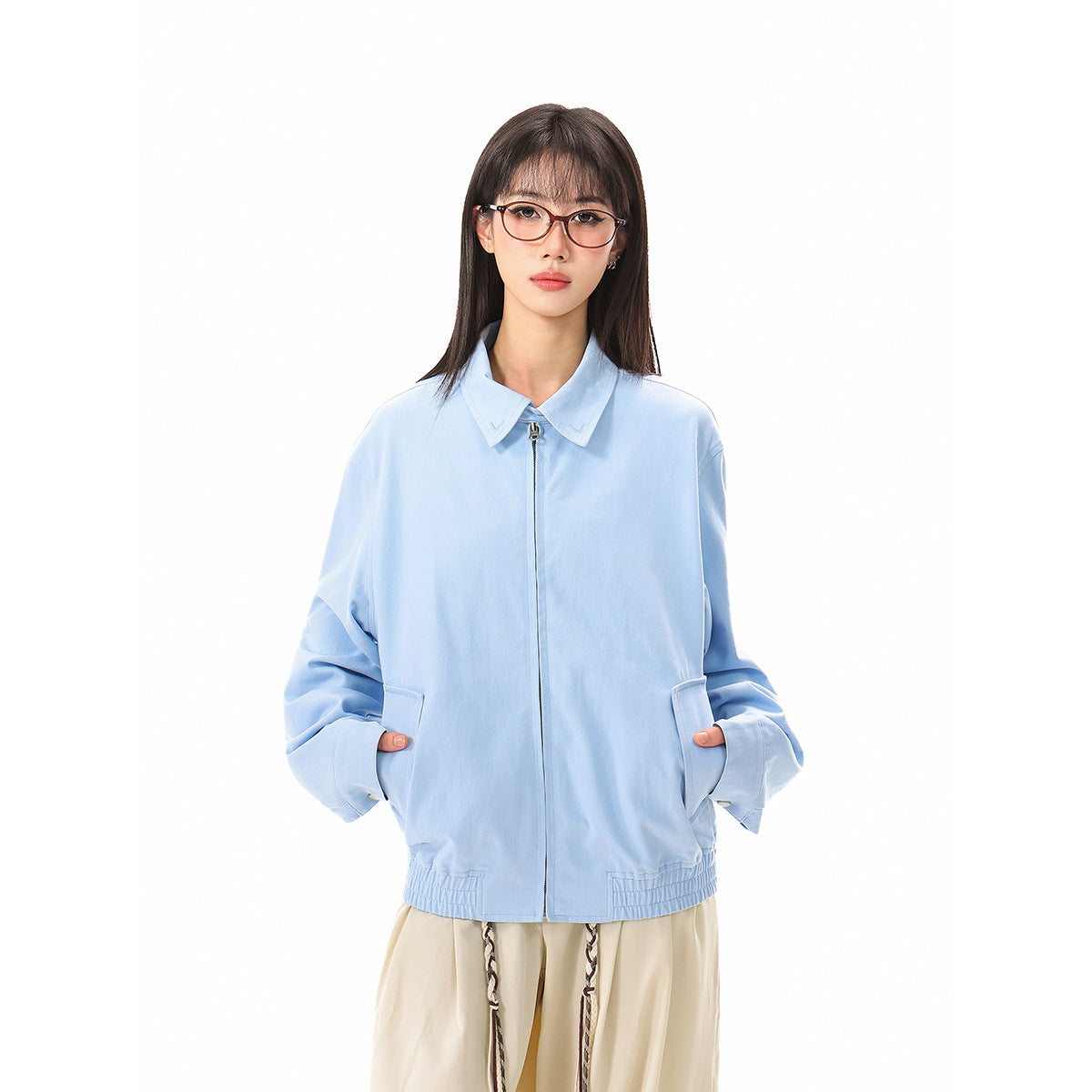 Front view of a model wearing an oversized light blue zip jacket with a pointed collar, roomy sleeves, and front pockets.