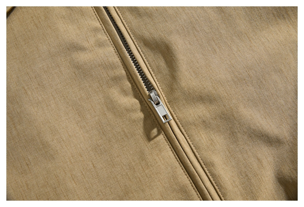 Close-up of the metal zipper on tan jacket fabric.