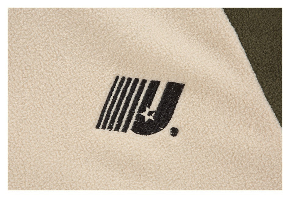 Close-up of a black stylized logo printed on the cream fleece jacket fabric.