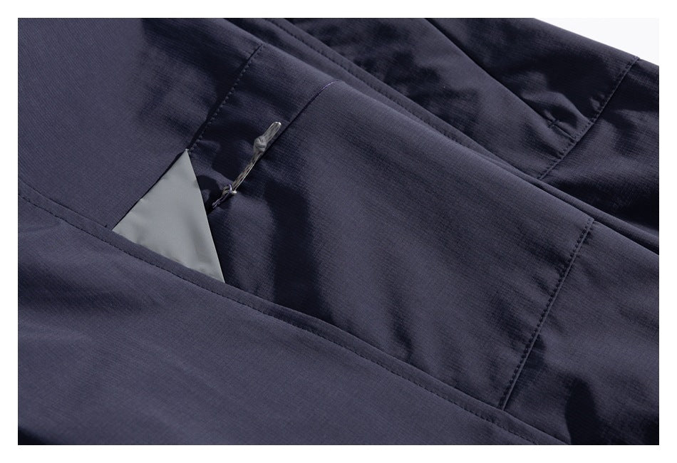 Close-up of a concealed pocket opening and zipper pull on the dark navy jacket.