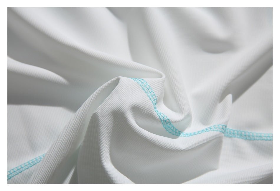 Close-up of softly gathered white textured fabric with turquoise stitching.