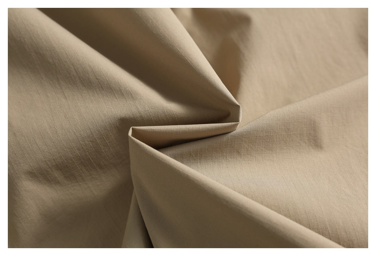 Close-up of tan fabric folded to show its subtle fine grid texture.