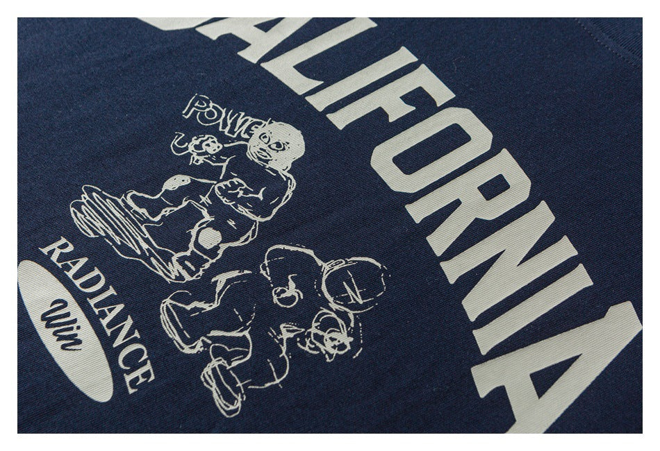 Close-up of a navy T-shirt graphic with large lettering and illustrated figures.