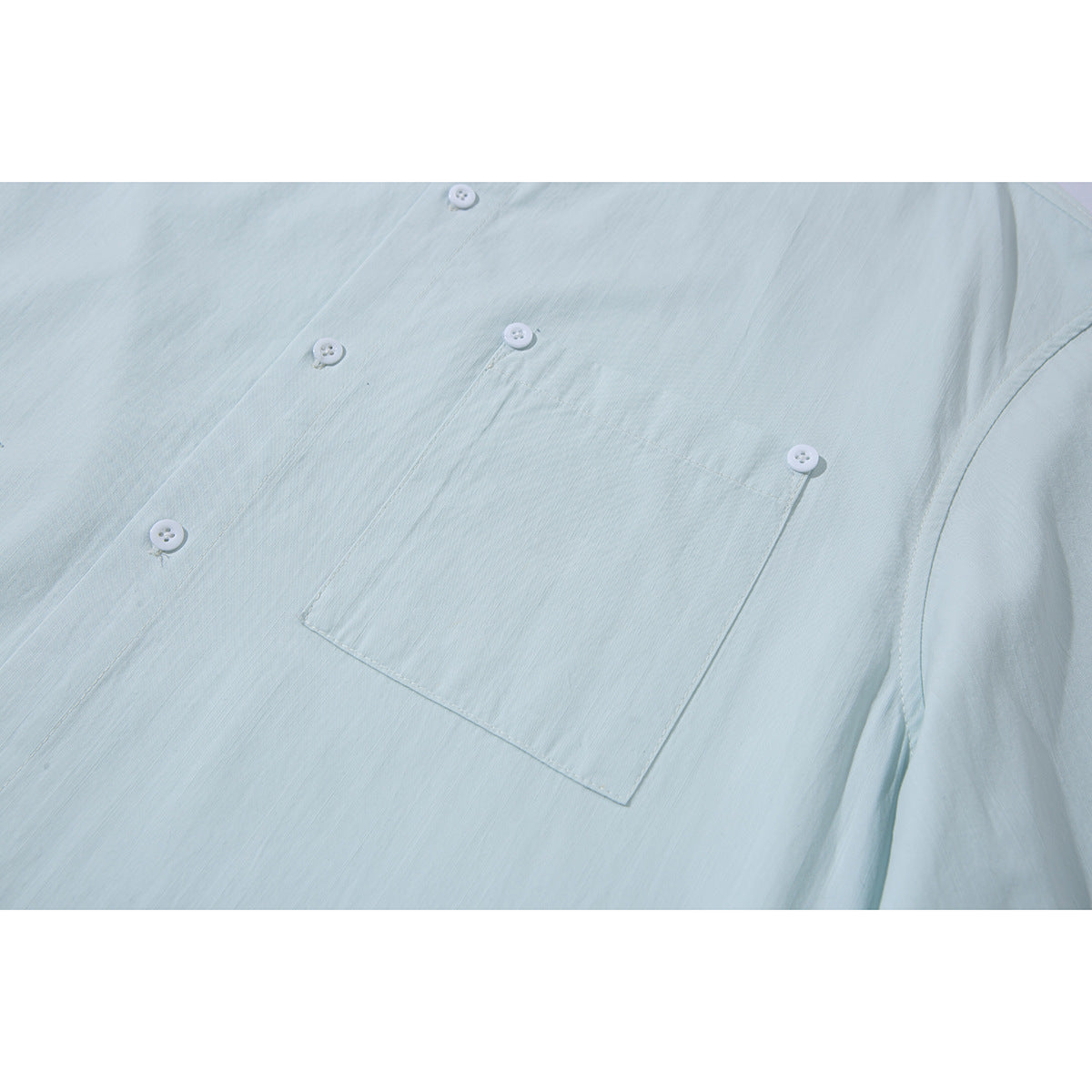 Close-up of a pale mint shirt front showing a single chest pocket and white buttons.