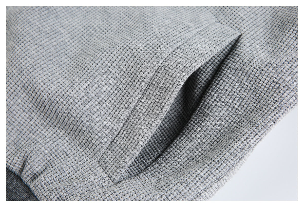 Close-up of a pocket opening on light gray textured fabric with dark charcoal trim.