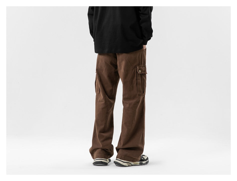 Rear view of a model wearing loose brown cargo pants with buttoned cargo pockets on both thighs.