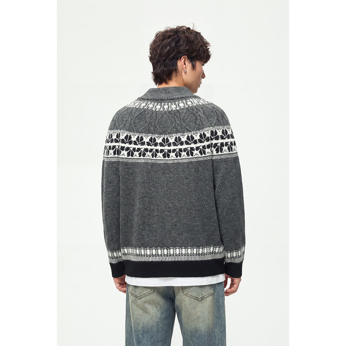 Back view of a model wearing a dark gray zip-up knit cardigan with white patterned bands and black ribbed trim.