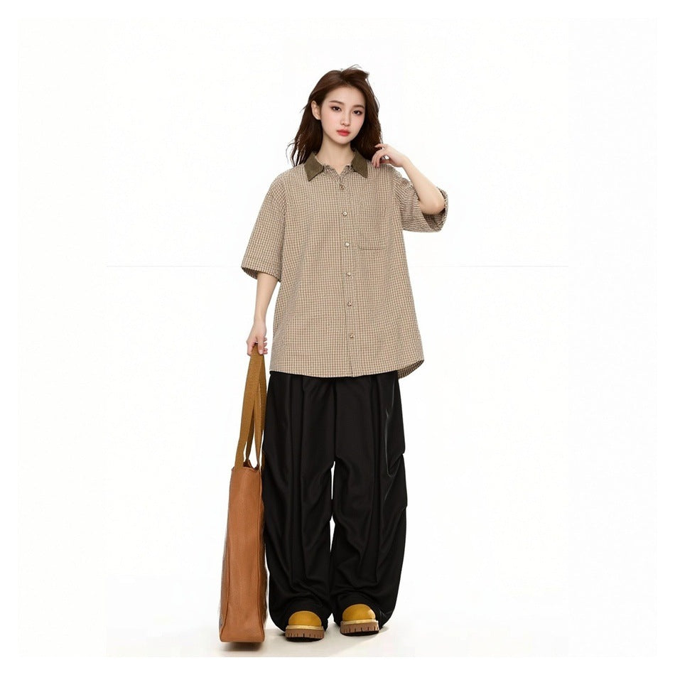 Model wearing the tan check short-sleeve shirt loose over black wide-leg pants, holding a tan tote bag
