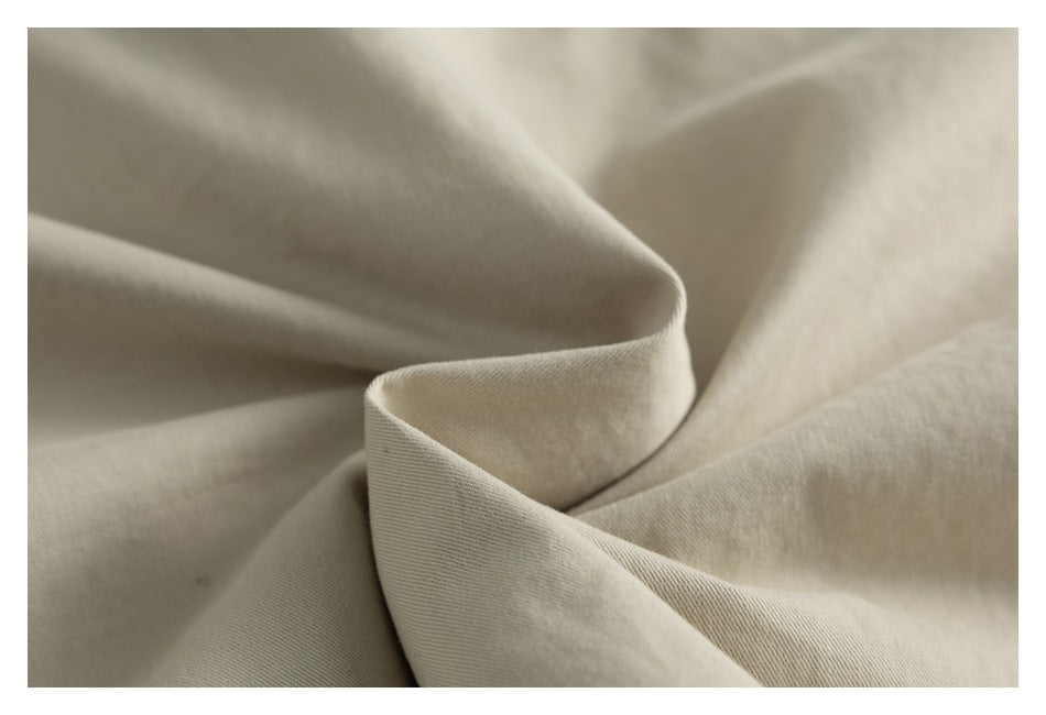 Close-up of softly folded beige garment fabric showing its fine surface texture.