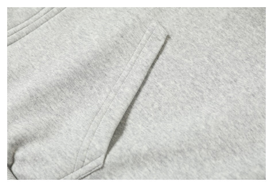Close-up of a diagonal pocket opening and stitching on a light heather gray garment.