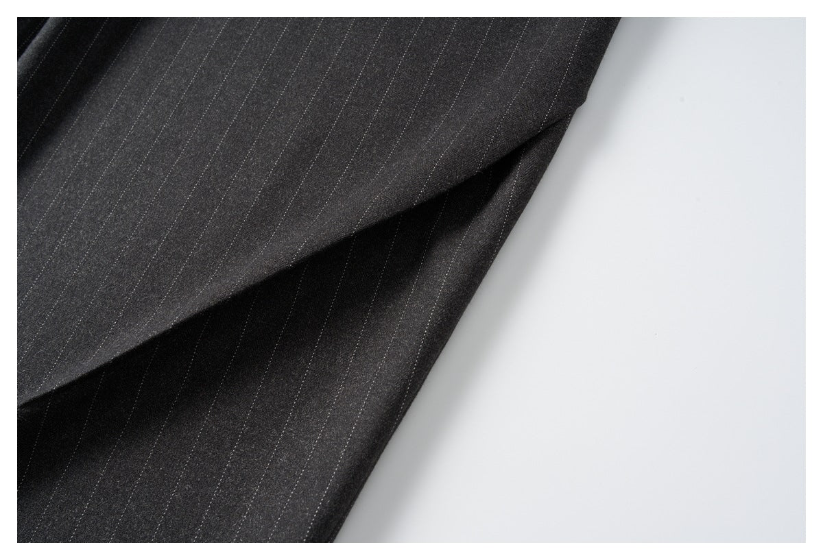 Close-up of folded charcoal pinstripe trouser fabric with a stitched seam.