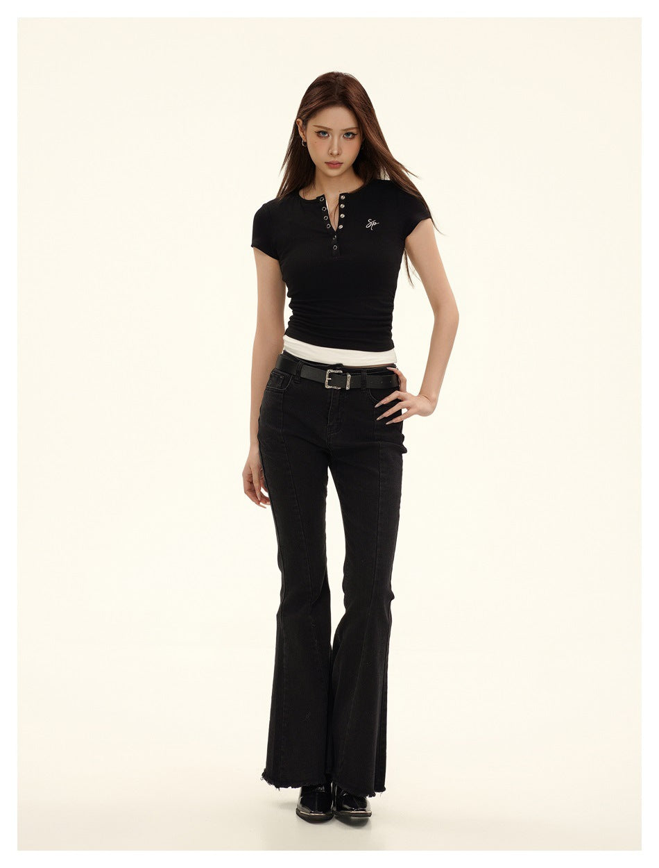 Model in black short-sleeve snap-placket top with white layered hem, paired with black flare jeans and belt