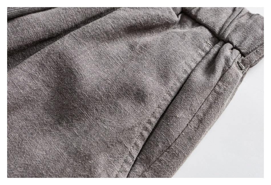 Close-up of light gray trouser fabric, waistband edge, and a stitched side seam.