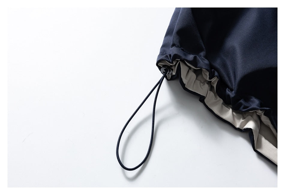 Close-up of a navy jacket's adjustable hem cord and light-colored inner lining.