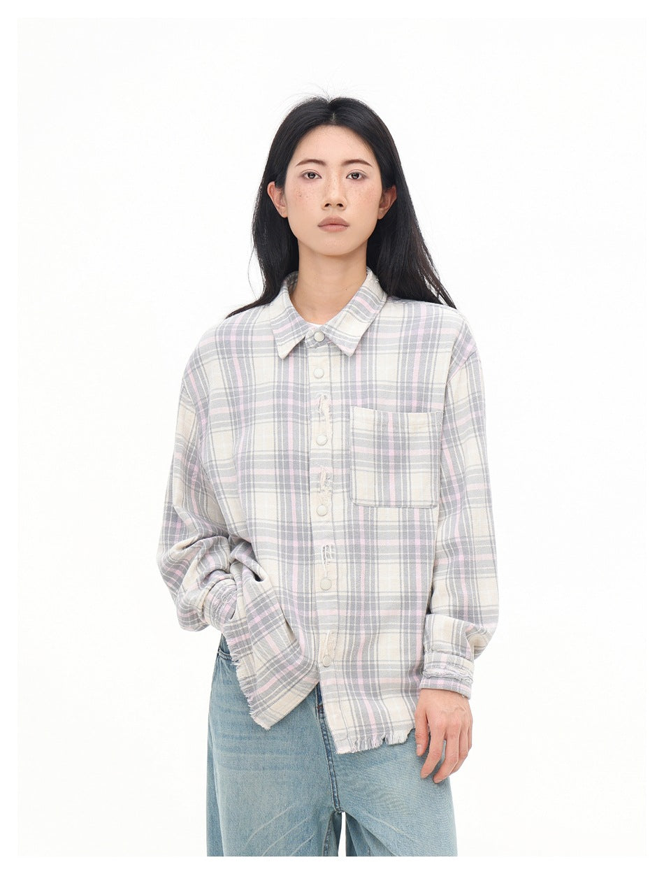 Model wearing a cream, gray and pale pink plaid shirt, showing its button front, chest pocket and frayed hem.