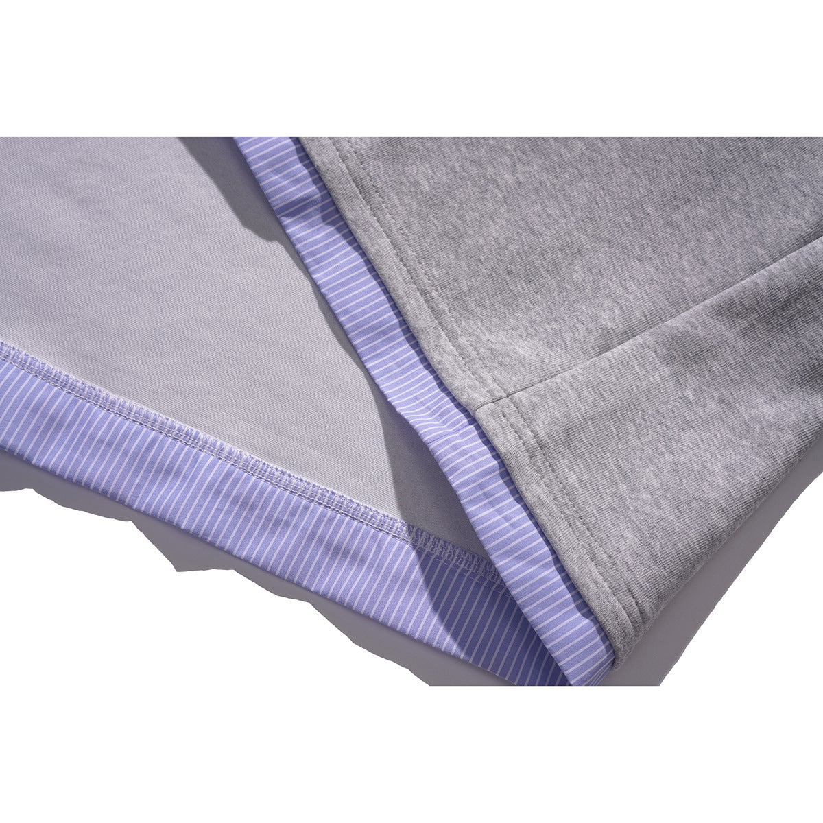 Close-up of a gray top's inner hem and seam with lavender striped fabric trim.