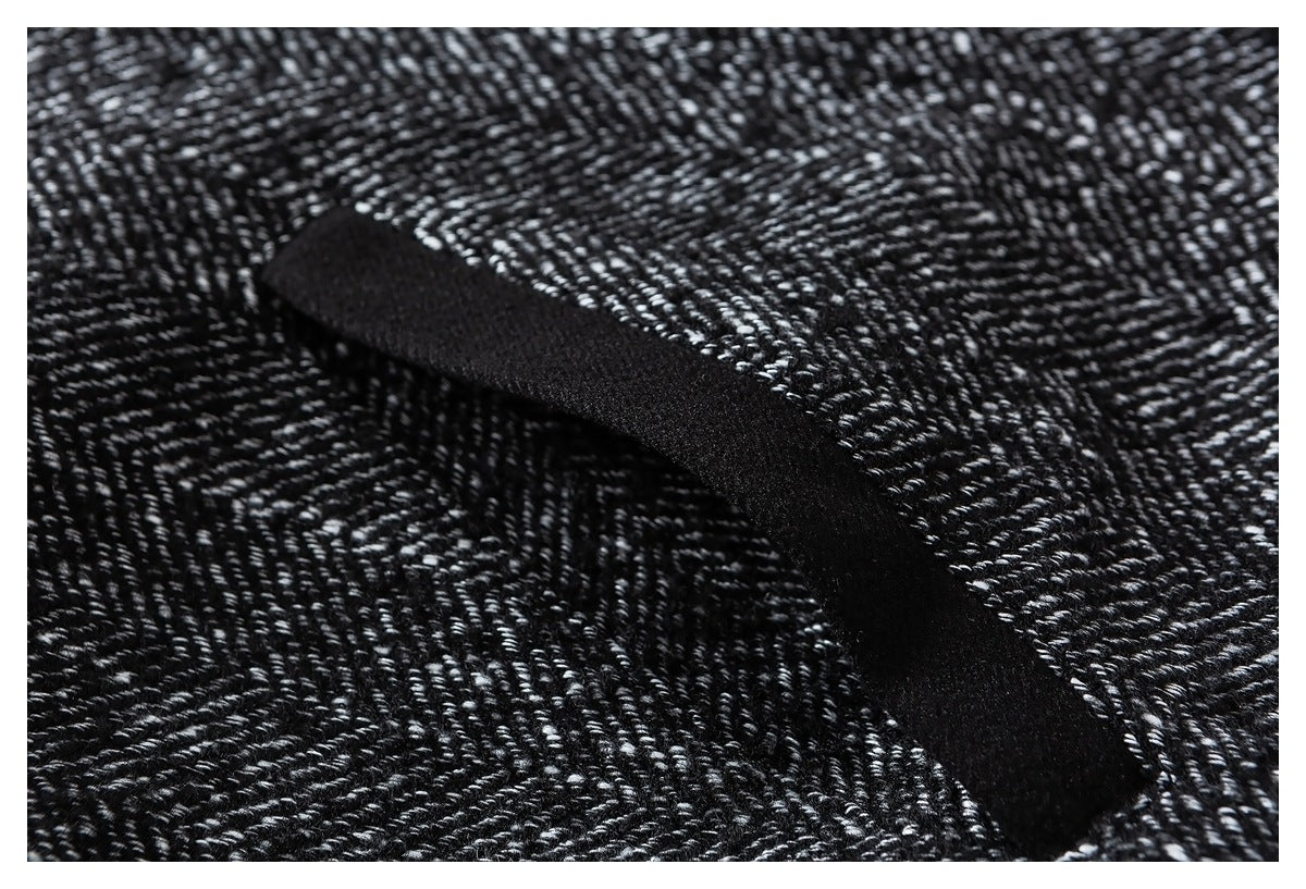 Close-up of black trim crossing the black-and-white herringbone jacket fabric.