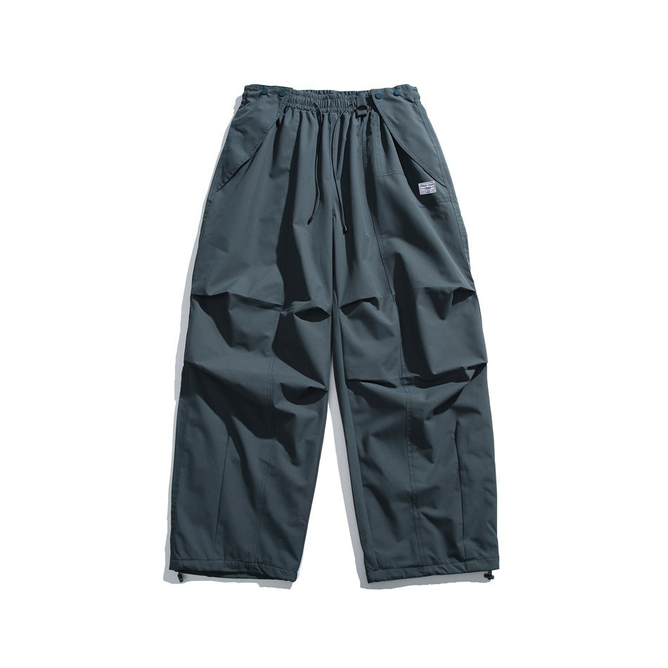 Front view of charcoal wide-leg pants with an elastic drawstring waist, angled pockets, knee panels and ankle toggles.