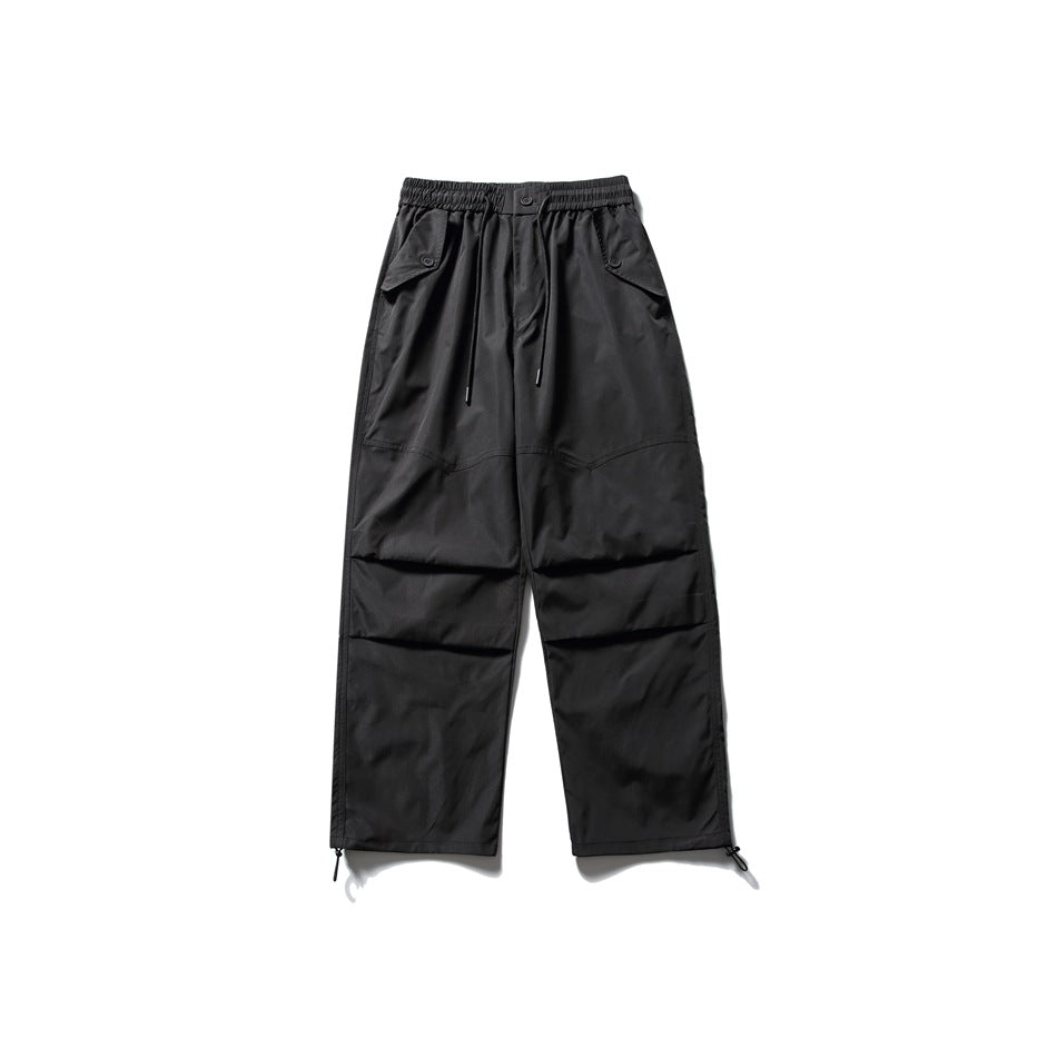 Black wide-leg parachute pants flat lay with drawcord waist, flap pockets, knee pleats and hem toggles