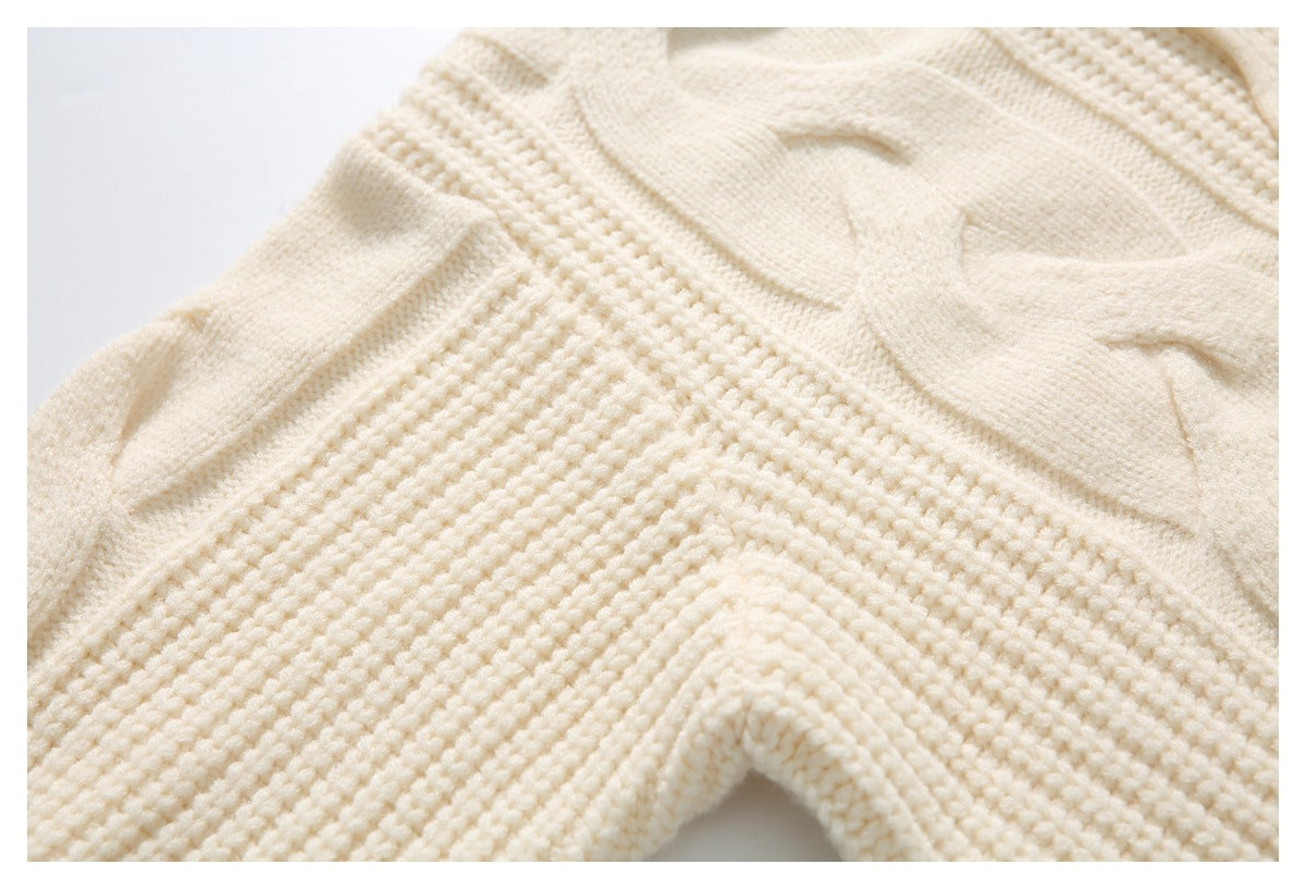 Close-up of an ivory knit cardigan showing raised cable patterns and textured stitches.