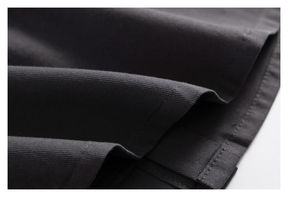 Close-up of layered dark charcoal fabric showing a folded, stitched garment hem.