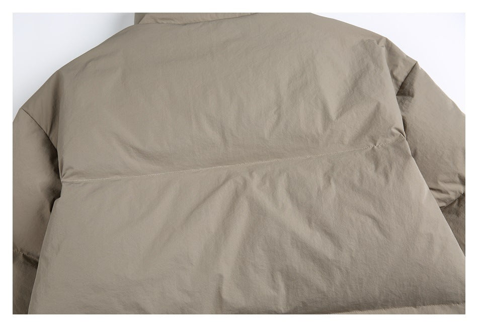 Back view of a plain taupe jacket laid flat, with long sleeves and a horizontal back seam.