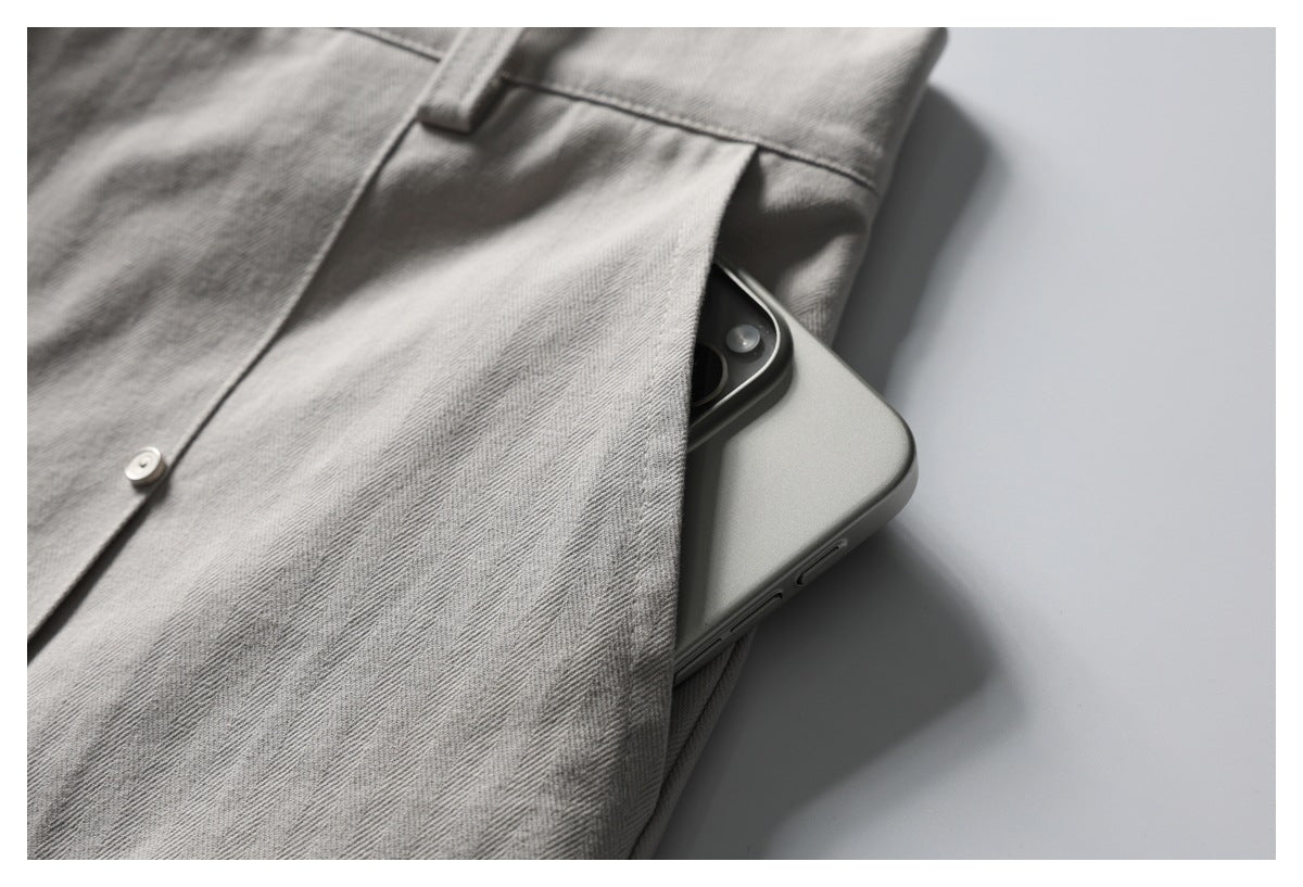 Gray herringbone trousers with a smartphone partly tucked into a side pocket.