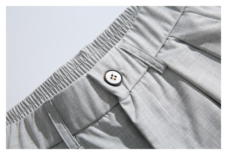 Close-up of the light gray trousers' waistband, belt loop, and four-hole button.