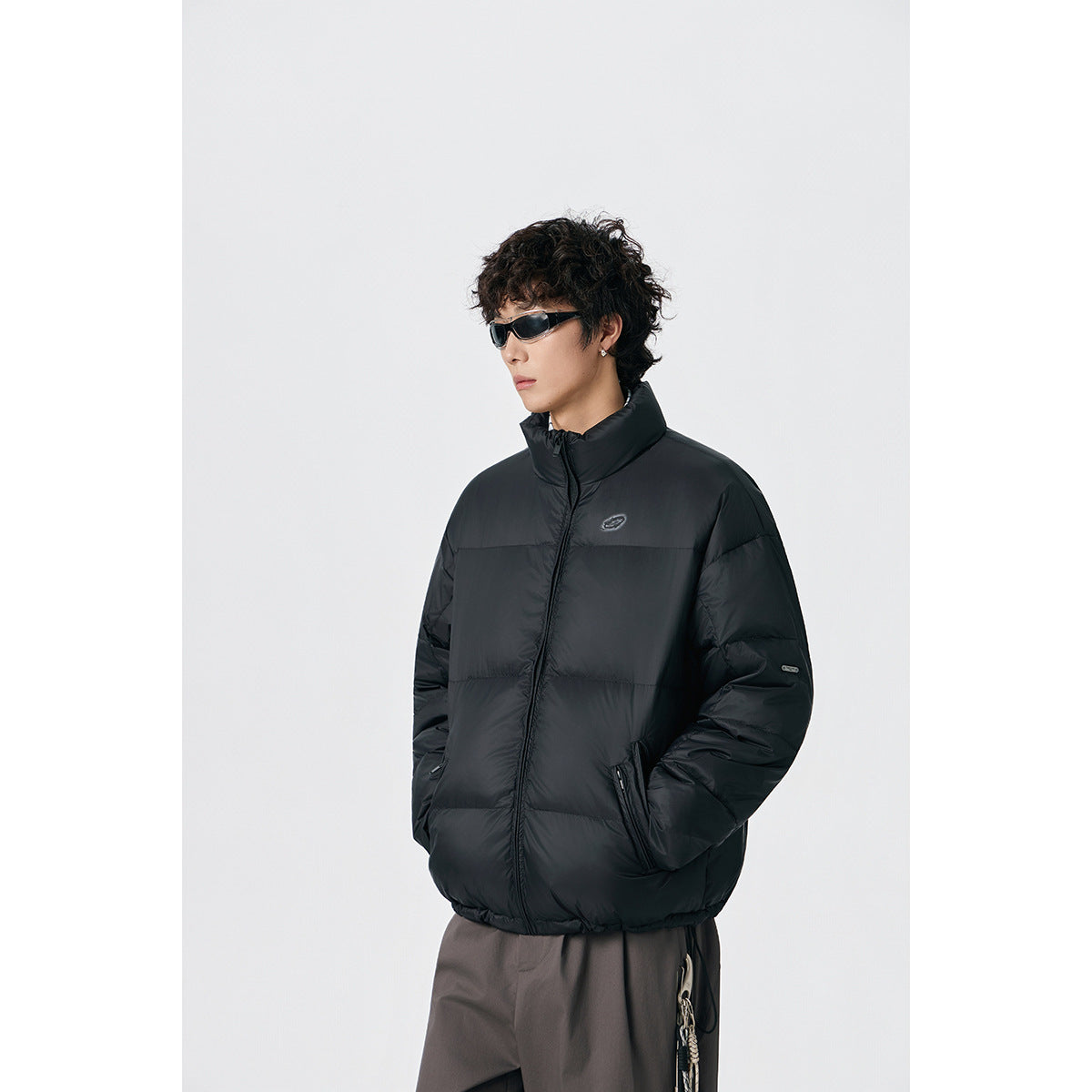 Model wearing a black padded jacket with a high stand collar and front zip pockets.