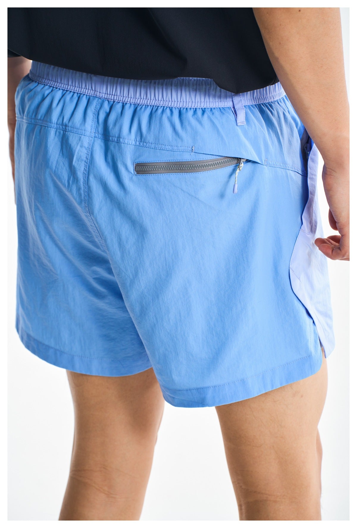 Close-up of the back of light blue shorts, highlighting the elastic waistband and gray zippered pocket.