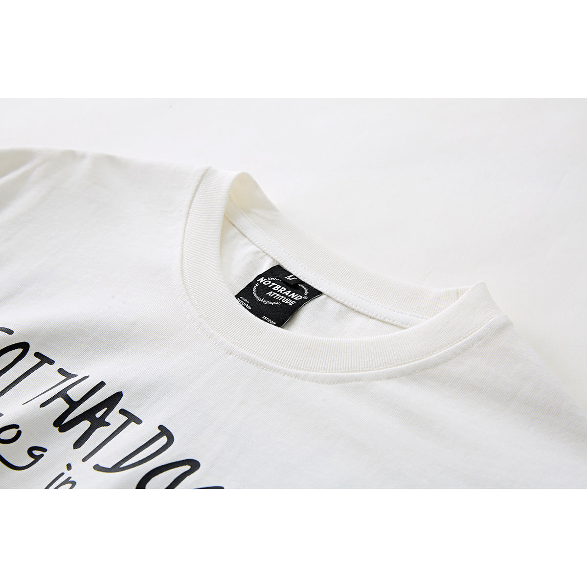Close-up of an off-white T-shirt collar, neck label, and partially visible black chest print.