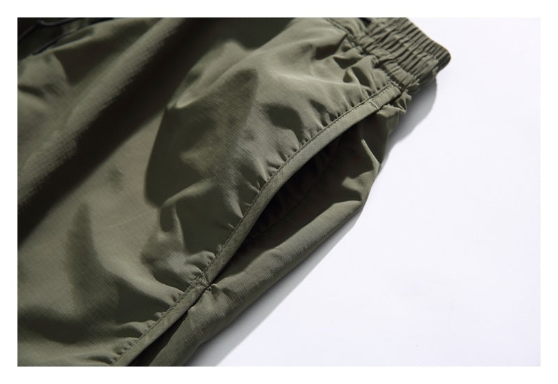 Close-up of olive-gray shorts showing an elastic waistband and curved stitched seam.
