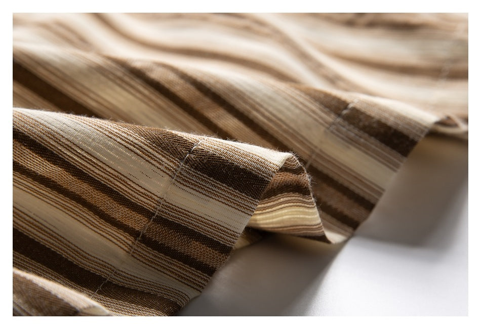Close-up of a folded edge with stitching on tan, brown, and cream striped fabric.
