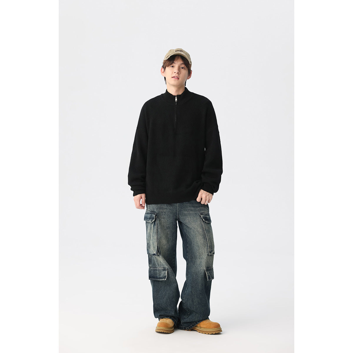 Full-length view of a model wearing a black ribbed quarter-zip sweater and loose cargo jeans.