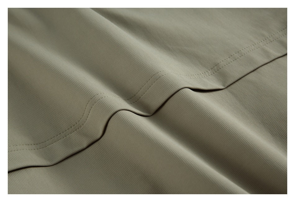 Close-up of curved stitching and a seam on olive-gray jacket fabric.
