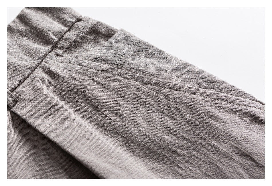 Close-up of a seam and textured woven fabric on light gray trousers.