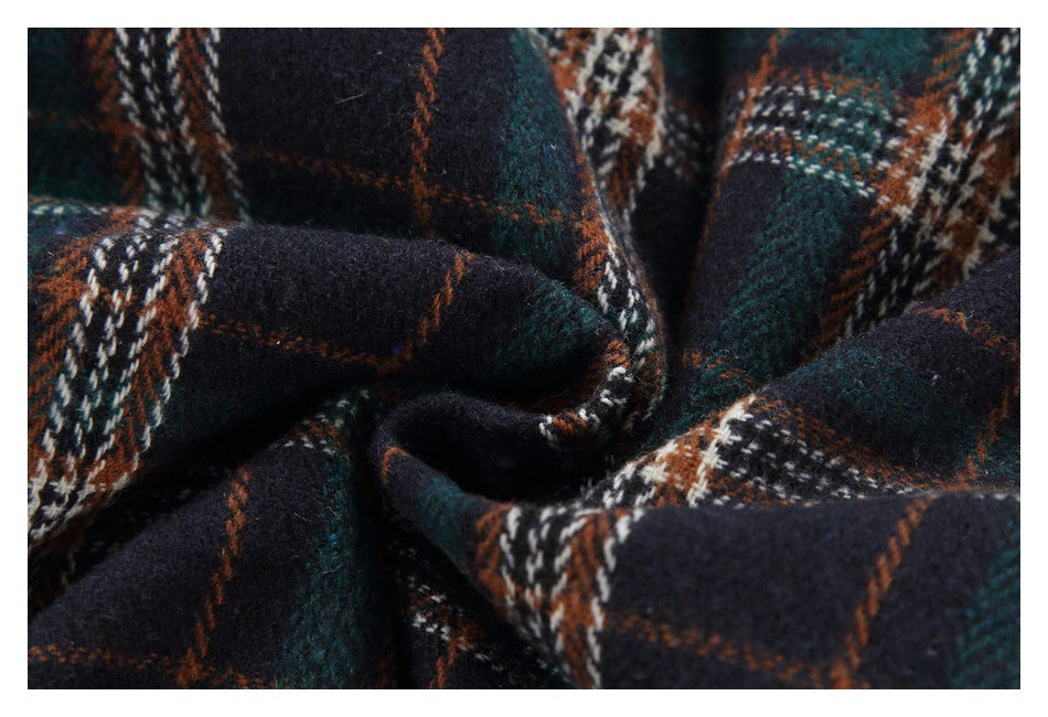 Close-up of dark navy plaid fabric with green, rust, and white intersecting stripes.