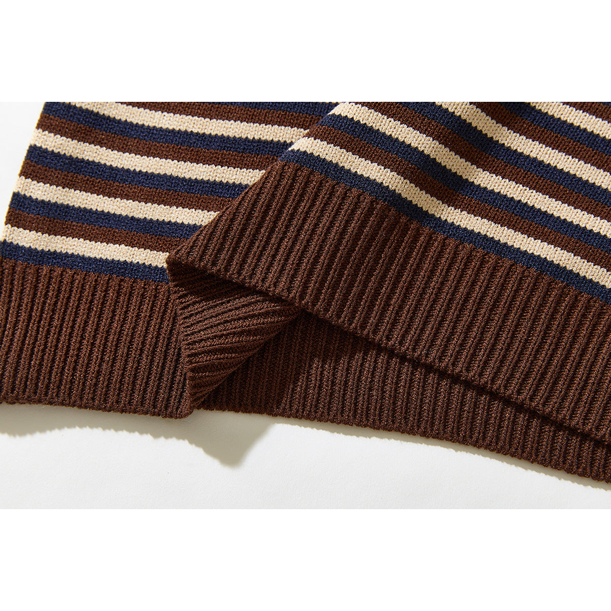 Close-up of the brown ribbed hem and cuff of a cream, navy and brown striped sweater.