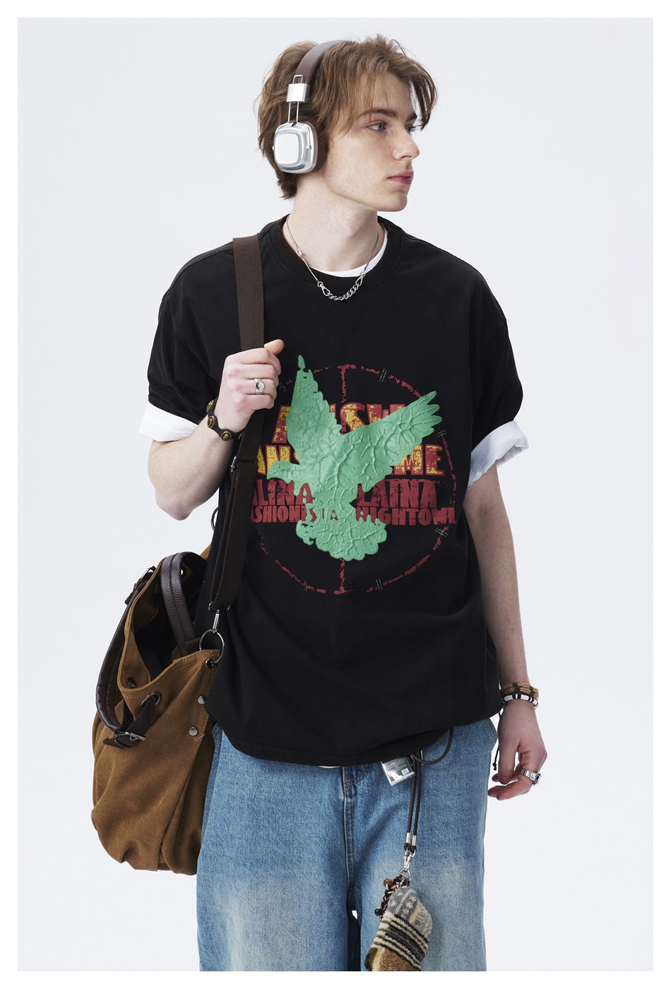 Close view of a model wearing a black T-shirt with white sleeve layers and a large raised green bird graphic.