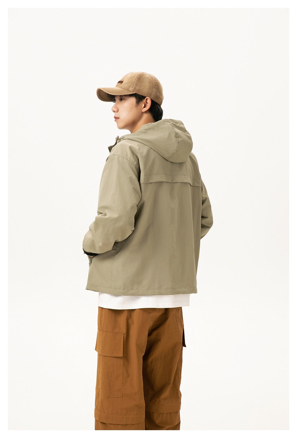 Side and back view of a model wearing the sage-gray hooded jacket with brown cargo pants.